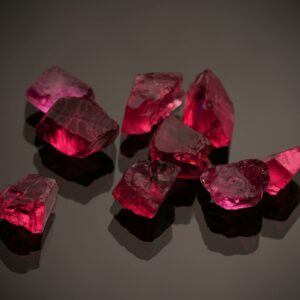 Close-up photo of vibrant red gemstones on a shiny black surface, showcasing brilliance.
